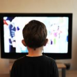 A male child facing a television