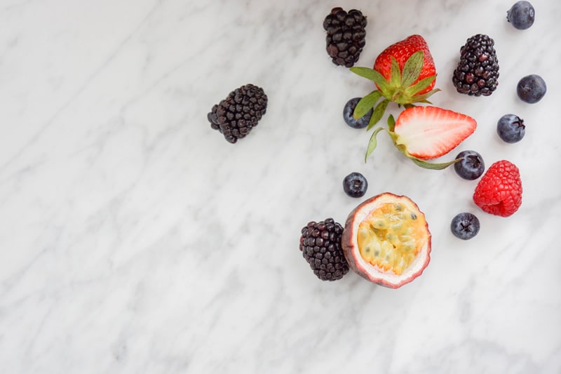 fresh berries and half of a passion fruit on a marble background