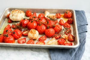 front view of baking sheet filled with cooked tomatoes and garlic