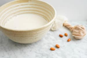 large ceramic bowl filled with almond milk and whole almonds on the side