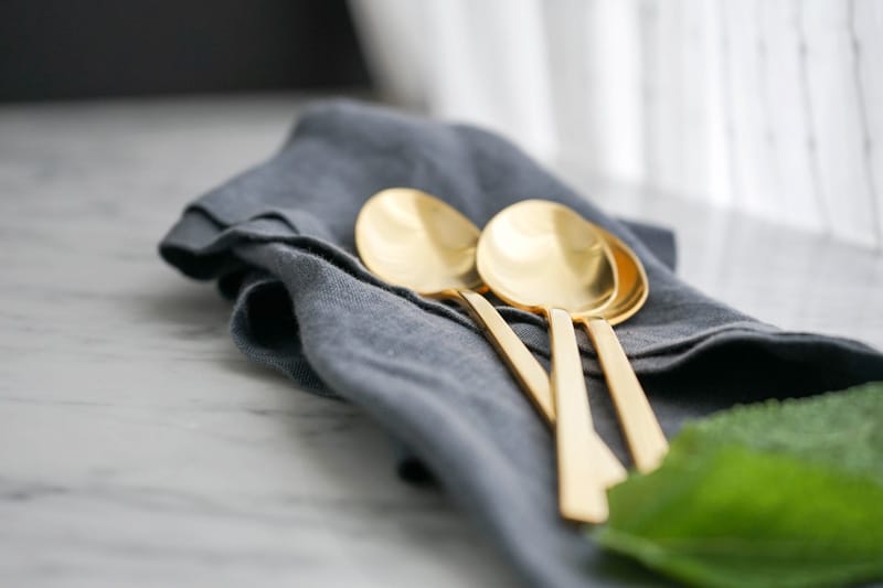 close-up of 3 golden spoons on a blue linen napkin
