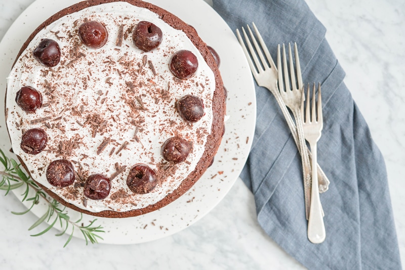 top down view of a chocolate cake with whipped coconut cream and cherries on top