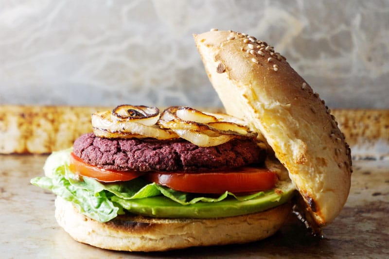 Burger with beet patty, roasted onions, tomato and lettuce