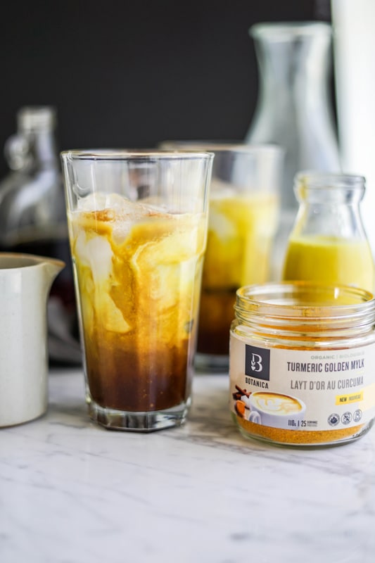 a glass of iced golden milk mocha latte beside a jar of Botanica's organic golden mylk